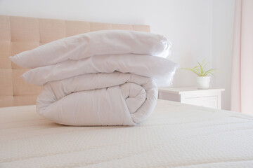 White duvet and pillows lying on bed in cozy bedroom at home. Seasonal bedding change and household...