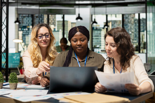 Group of diverse business partners engaging in collaboration during briefing session, analyzing data and writing reports while embracing a mindset of growth. Goals oriented meeting in office.