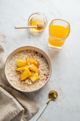 Oatmeal with peaches and nuts  in a bowl on a marble background with honey