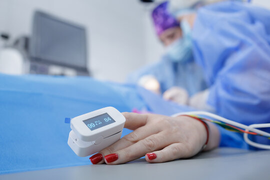 Pulse oximeter on patient hand monitoring oxygen saturation during surgery