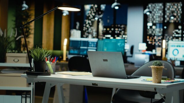 Modern empty office glows with the light of performance metrics and forecasting graphs. Corporate space equipped with technology and computers reflects administration of enterprise objectives.