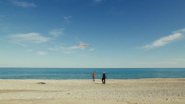 Father and son playing with kite near the ocean on the beach for the day