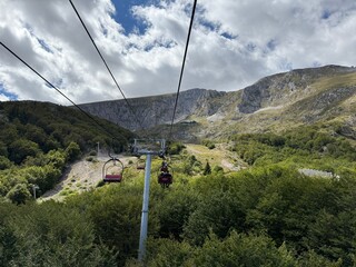 Landscape photo of Montenegro mountains seen from a cable car window showing dramatic peaks and vast scenic terrain below.