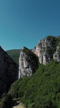 Close aerial view of dramatic rocky cliffs in Jerma Canyon mountains, Serbia country, surrounded by dense forest. Vertical 4k footage