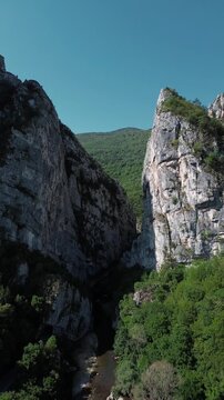 Close aerial view of dramatic rocky cliffs in Jerma Canyon mountains, Serbia country, surrounded by dense forest. Vertical 4k footage