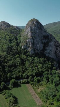 Close aerial view of dramatic rocky cliffs in Jerma Canyon mountains, Serbia country, surrounded by dense forest. Vertical 4k footage