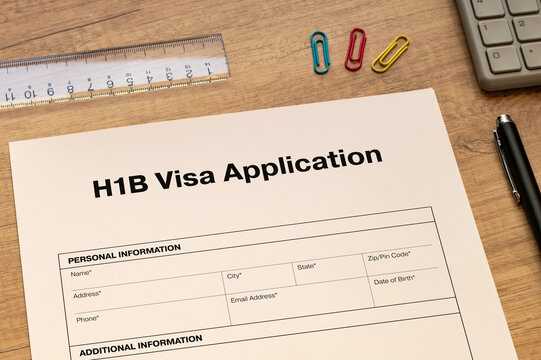 The document of the H1B Visa Application is on the desk, along with a calculator and a pen.