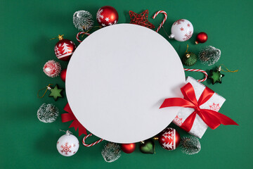 Festive Christmas composition with gifts, balls and fir branches on green background. White circle...