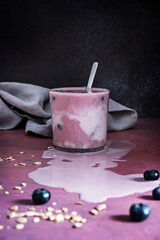 Bowl of perfect blueberries and a blueberry and spinach smoothie on a light, luminous maple wood board