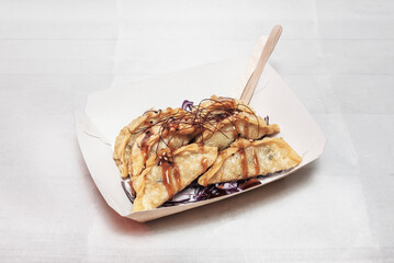 Crispy gyozas filled with confit duck, spring onion, and hoisin sauce, presented on a bamboo tray
