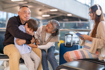 Asian multigenerational family at airport traveling with kids and grandparents, joyful moments of...