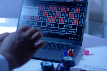man hands with Gambling Chips using laptop for playing online casino. Concept virtual leisure activity. Person playing online poker and looking winning cards. Concept win and lose in casino