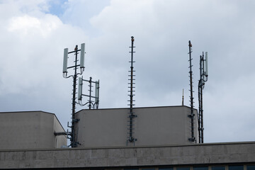 Telecommunications antennas mounted on a building rooftop against a cloudy sky, showcasing modern technology and infrastructure for communication networks and connectivity solutions