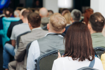 Audience at the modern conference hall listens to panel discussion, people on a congress together listen to speaker on stage at convention, plenary session at business seminar, venue for presentation