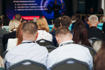 Audience at the modern conference hall listens to panel discussion, people on a congress together...