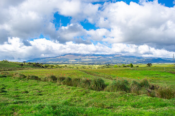 Fototapeta premium Scenic view of lush green fields with mountains under a stunning cloudy sky in Puracé, Cauca, Colombia.
