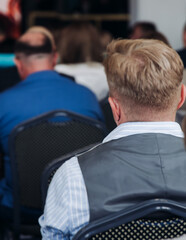 Audience at the modern conference hall listens to panel discussion, people on a congress together...