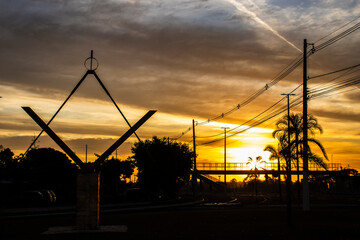 Silhouette of the Masonic Square and Compasses monument against a dramatic golden sunrise sky in a...