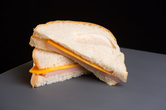 Bologna and cheese sandwich on white bread halved on a plate