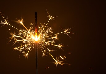 Obraz premium Sparkling Celebration - A Close-Up of a Lit Sparkler Against a Dark Background.