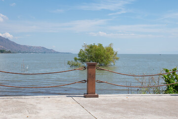 Peaceful view from Jocotepec boardwalk showing calm lake water, mountain range and railing