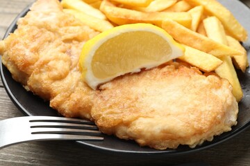 British Traditional Fish and chips served with lemon on wooden table, closeup