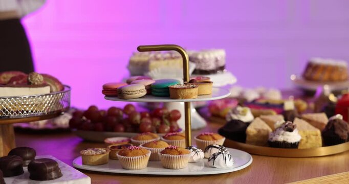 Waiter near buffet table with many different desserts and drinks indoors, closeup. Camera moving right