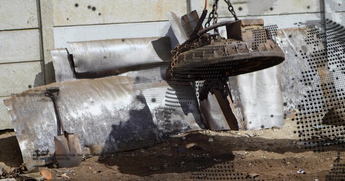 Hoisting heavy round metal component by chains in scrapyard, with corrugated sheet and shovel