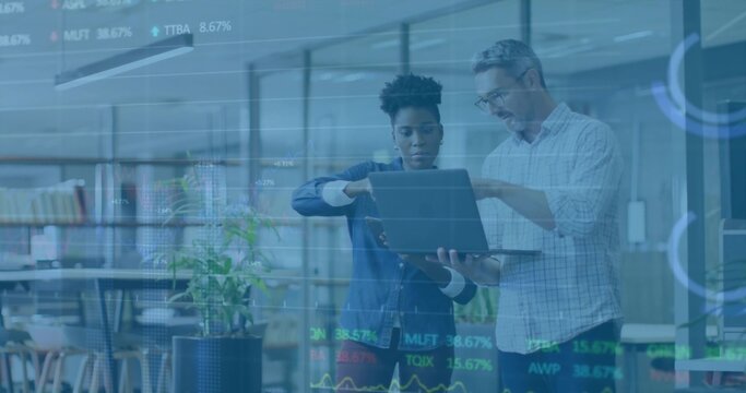 Colleagues analyzing stock market charts on laptop in modern office, with glass partition