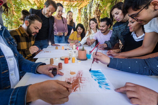 group of latin people in painting classes in a terrace outdoors in Mexico Latin America, multi generational Hispanic and diverse team meeting in art classes 
