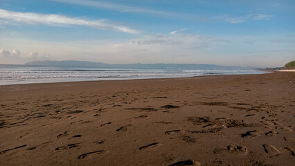 Beach view with the sky color dominated by bright blue with a few streaks of white clouds