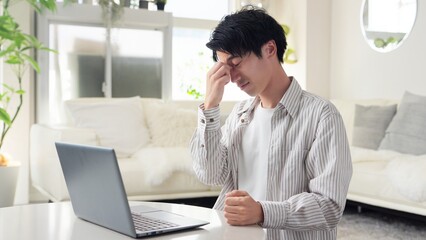 パソコン作業で目が痛くなるアジア人男性