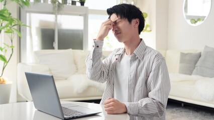 パソコン作業で目が痛くなるアジア人男性