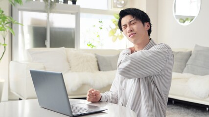 パソコン作業で肩が痛くなるアジア人男性