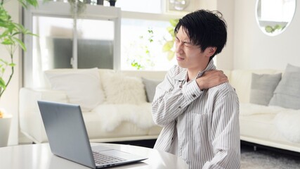 パソコン作業で肩が痛くなるアジア人男性