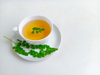 Moringa or Daun kelor herbal drink. A cup of Moringa tea. Boiled moringa leaves water in cup on white background. Healthy drink lifestyle