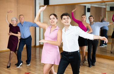 Fototapeta premium Couple of young dancers rehearsing ballroom dances in dance studio