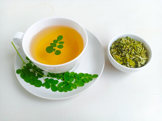 Moringa or Daun kelor herbal drink. A cup of Moringa tea. Boiled moringa leaves water in cup on white background. Healthy drink lifestyle