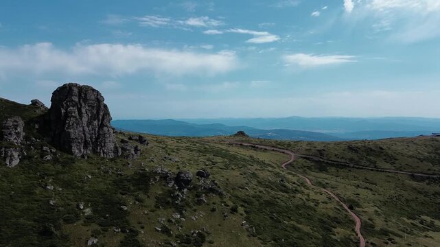 Rocky peaks of Babin Zub mountain in Stara Planina National Park, Serbia, rise above green forests under a blue sky. Aerial view from drone. Horizontal 4k footage