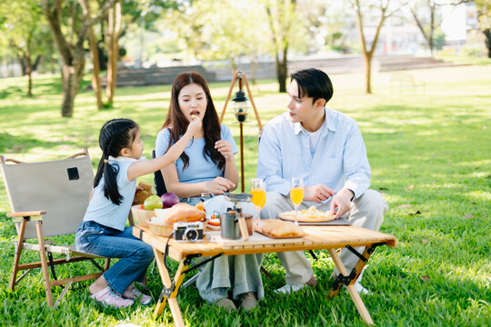 Joyful family picnic breakfast in a sunny green park with food and juice. A warm lifestyle moment filled with love, laughter