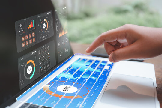 Hand interacting with holographic dashboards on a laptop keyboard; real-time analytics, smart-home monitoring, and IoT control for data-driven decisions