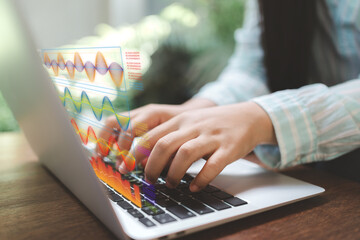 Hands typing on laptop with holographic data visualization charts; concept of data analytics, AI-driven insights, and digital work