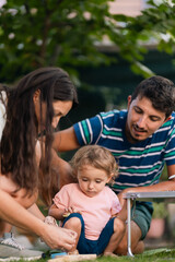 Naklejka premium Young parents spending playful moments with their toddler outdoors