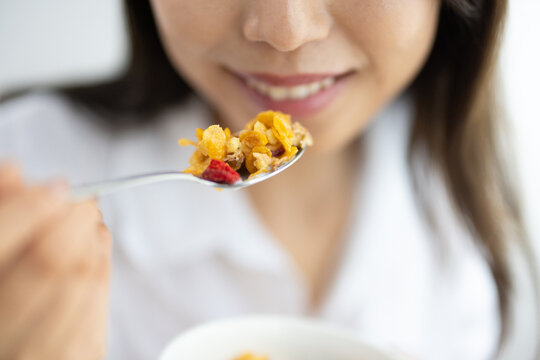 Close-up of cereal on spoon held by smiling woman