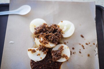 Spicy Tradition: Kuih Piring Rice Cakes with Sambal Topping on Wax Paper