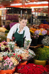 Woman flower shop assistant collects carnations into a bouquet