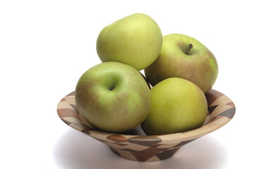 Green apples in a wooden bowl.   The apples are on a white background.  The look is simplistic. The subject is to the right of frame.