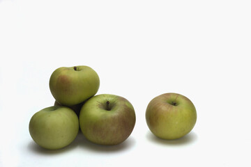 Green apples on a white background.  Horizontal layout.  The apples are piled to the left of frame with a single apple near mid frame. There is ample blank space for text.