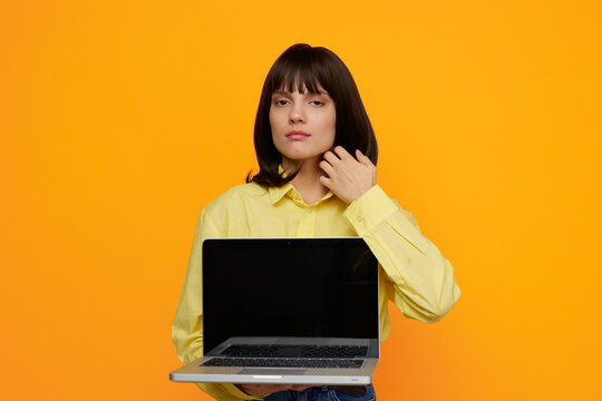 Female professional stands against a vivid orange backdrop, presenting a laptop. The scene conveys remote work, online learning, and creative digital tasks with clarity.