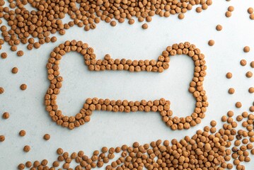 Obraz premium A bone shape consisting of dog food pellets on a light background -generated by ai
